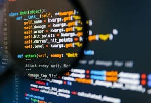 Programkód a számítógép kijelzőjén nagyítóval.