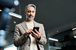 Középkorú üzletember egy telefont néz.