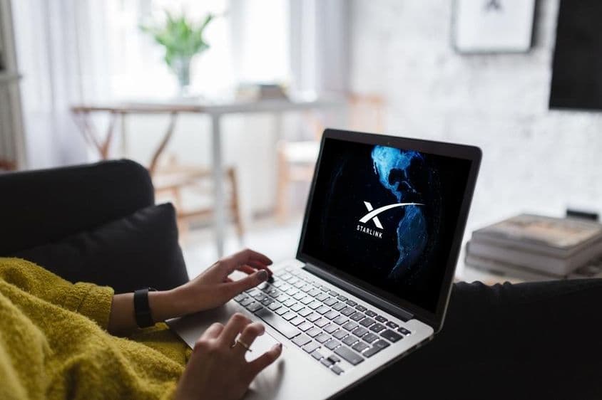 Egy laptop kijelzőjén starlink logó és a föld térképét ábrázoló globális műholdas internet.