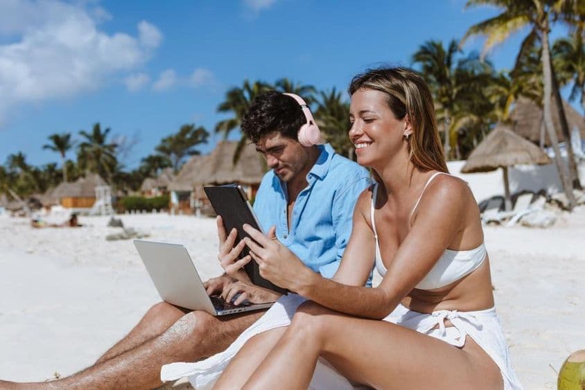 Fiatal pár digitális nomádok dolgoznak a strandon.