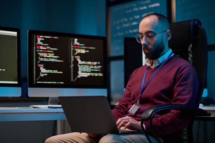 Szakállas felnőtt férfi szemüveget visel és laptopot használ.