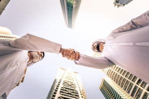 Kandurával rendelkező arab üzletemberek csoportja a szabadban találkozik.